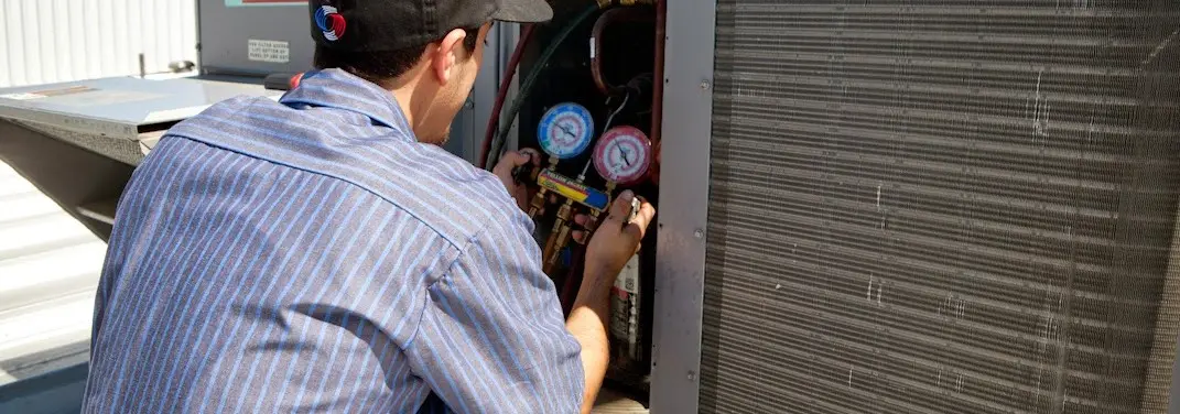 HVAC technician servicing a condenser unit in Travis Ranch