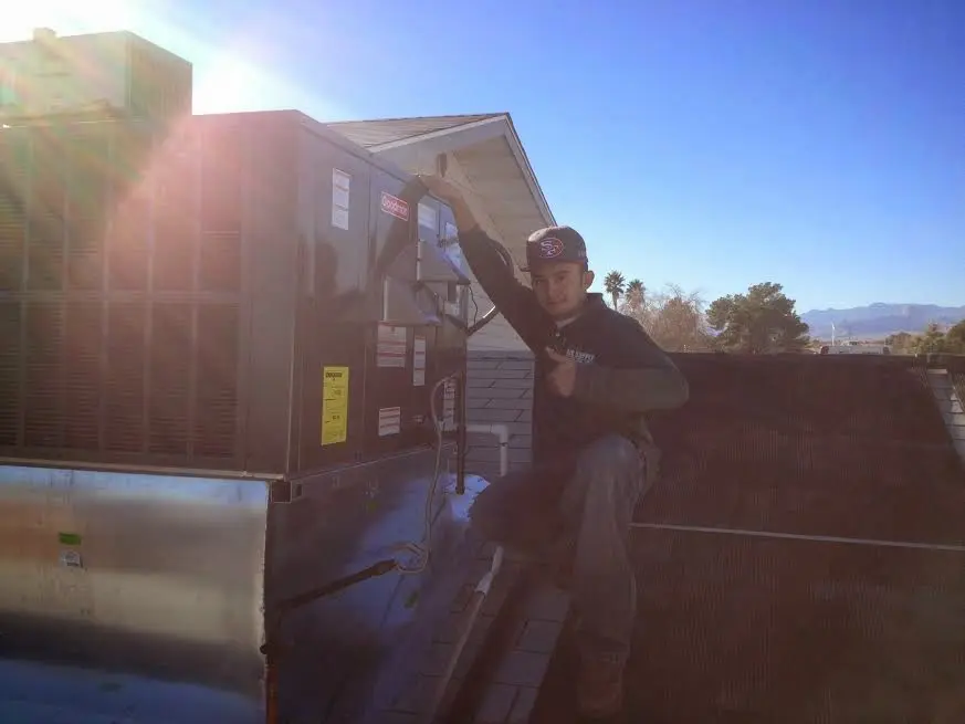 HVAC technician performing Air Duct Cleaning on a rooftop unit in Travis Ranch